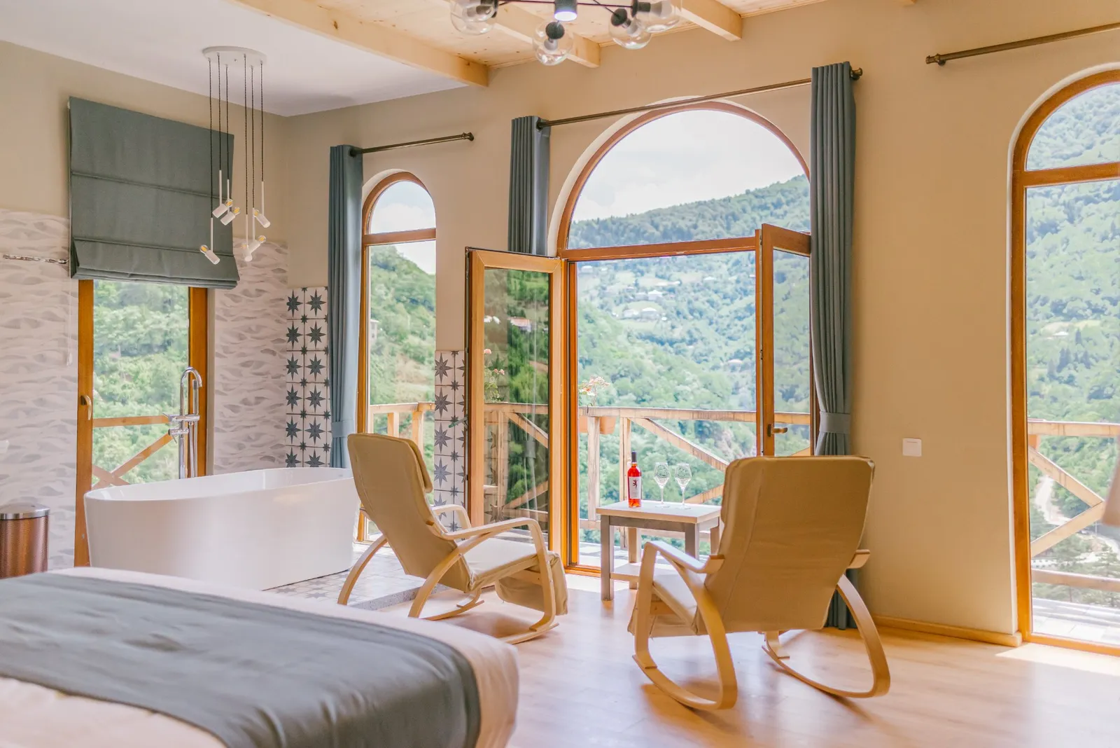 A room at Hotel Chateau Iveri with arched windows and a balcony over the green valley