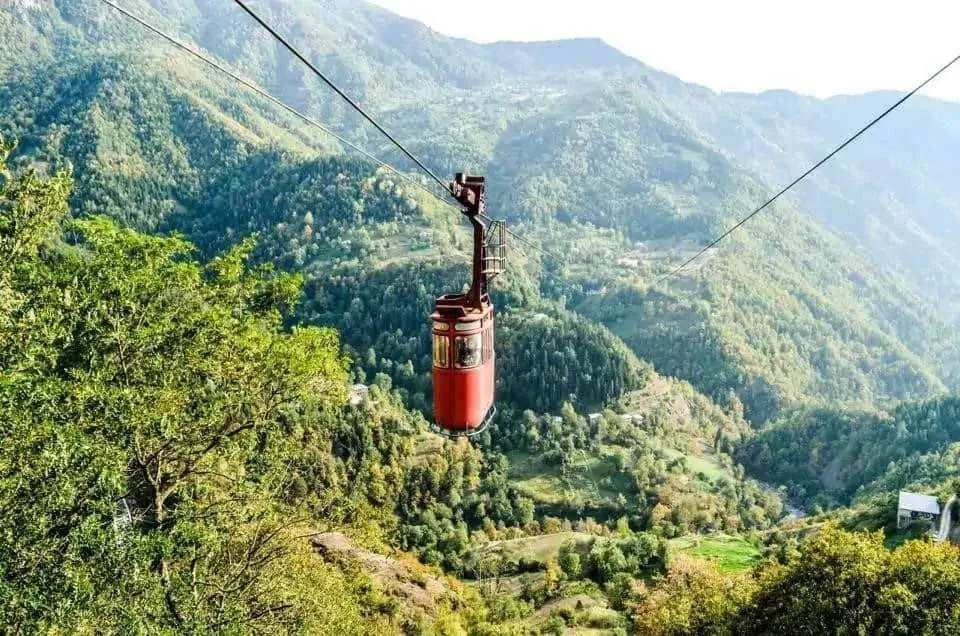 The red Khulo to Tago cable car cabin on its line over the green gorge