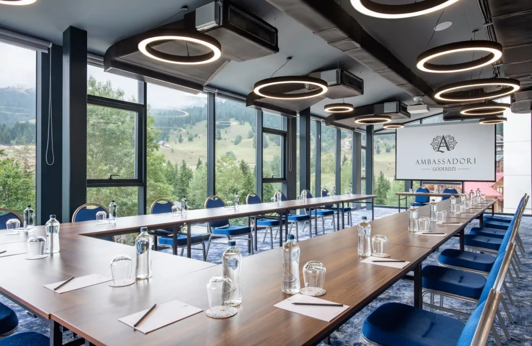 A conference room at Hotel Ambassadori Goderdzi set with long tables and forest views
