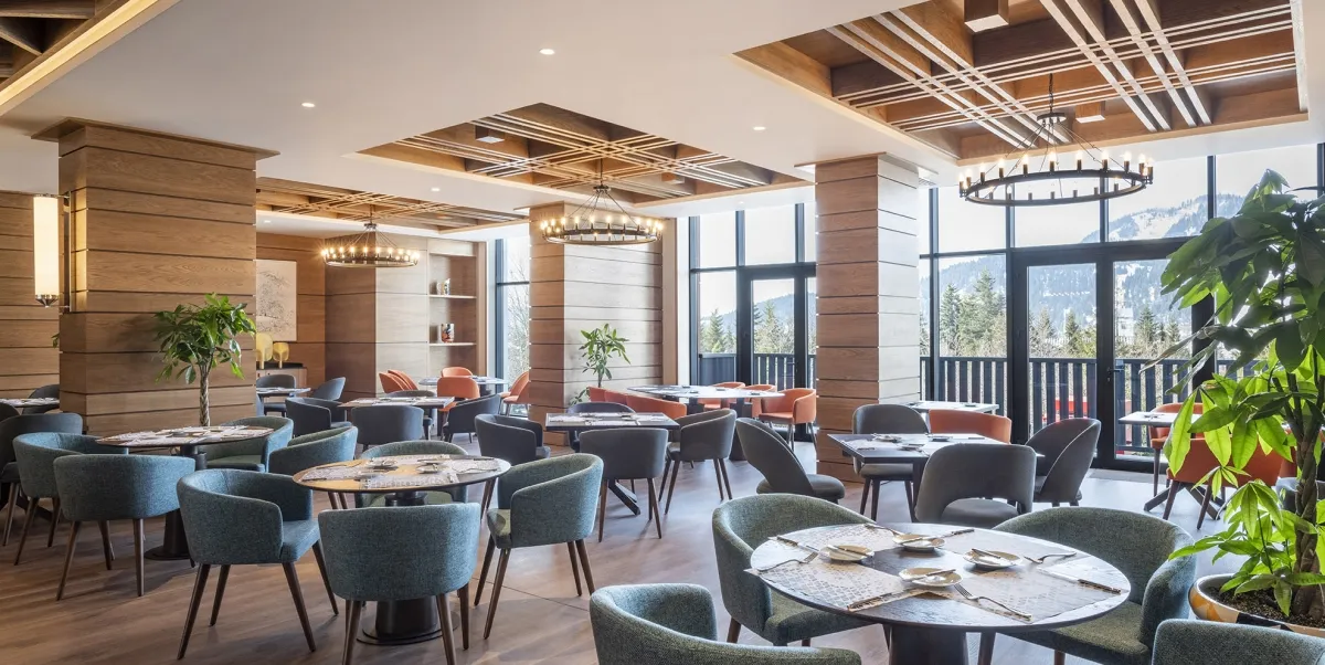 The a la carte restaurant of Hotel Ambassadori Goderdzi with mountain views through tall windows