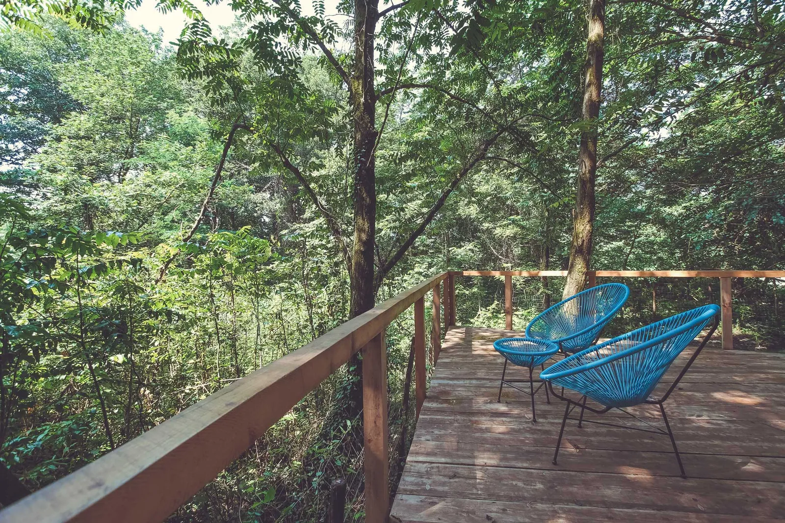 A wooden deck with two chairs among the trees at Duende in Lagodekhi