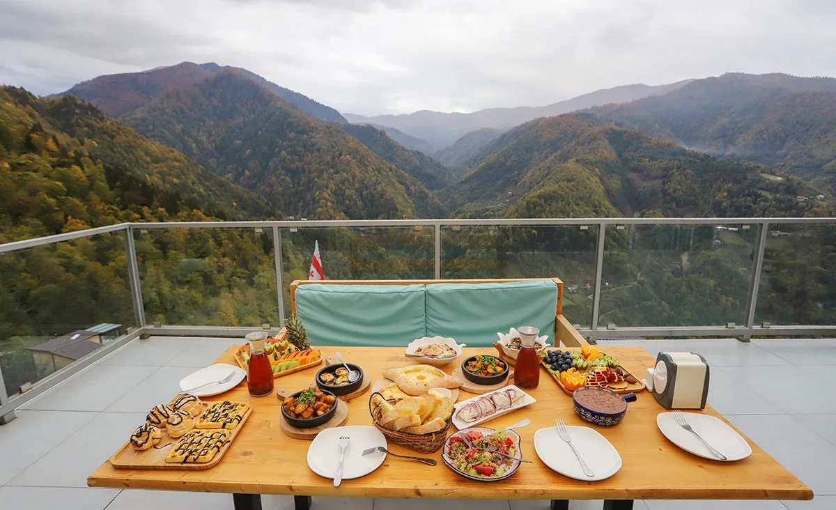A table laid with Georgian dishes on the restaurant veranda of Eco House Merisi above autumn forest