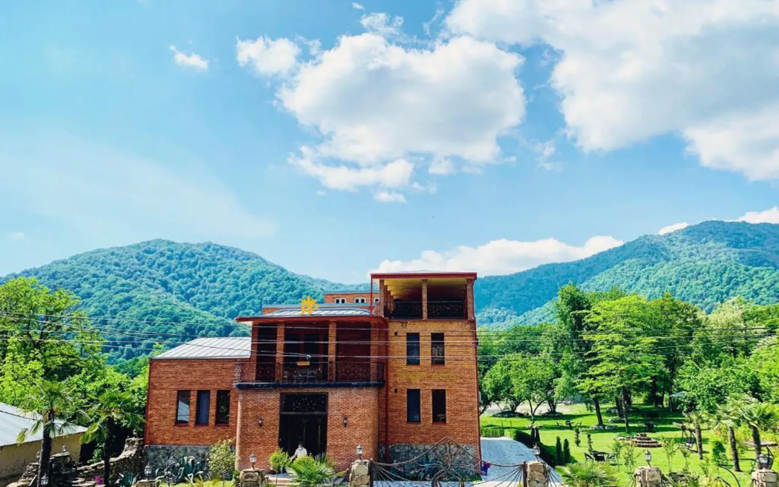 The brick main building of Royal Palace in Lagodekhi with green hills behind