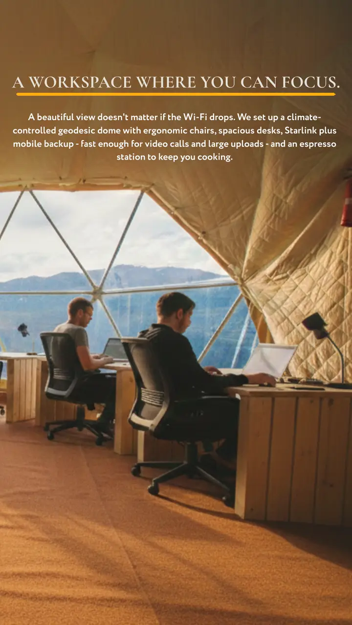 Two people working on laptops at wooden desks inside a geodesic dome with mountain views