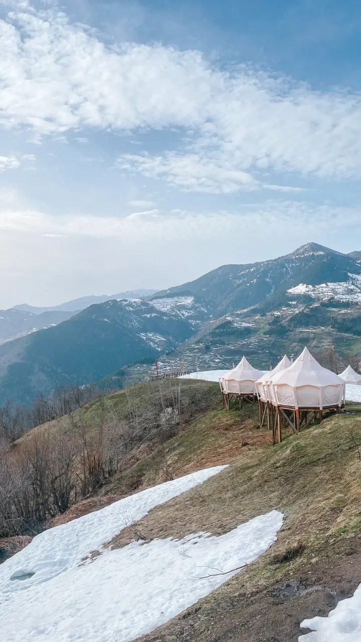 გლემპინგის კარვები ფერდობზე, მთებზე ბოლო თოვლით მარტის ბოლოს