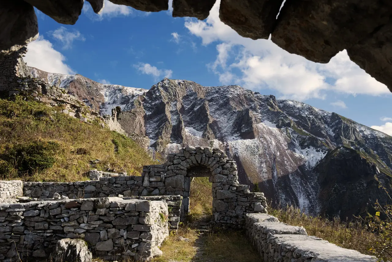 A stone arch in the walls of Khikhani fortress with rocky peaks behind