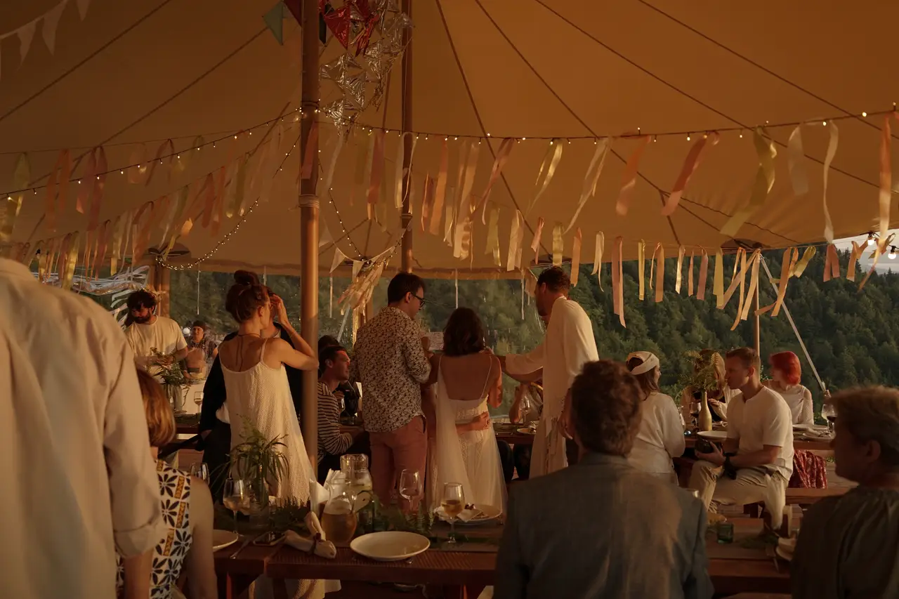 A group dining under the large event tent at Glamping Tago with mountains behind