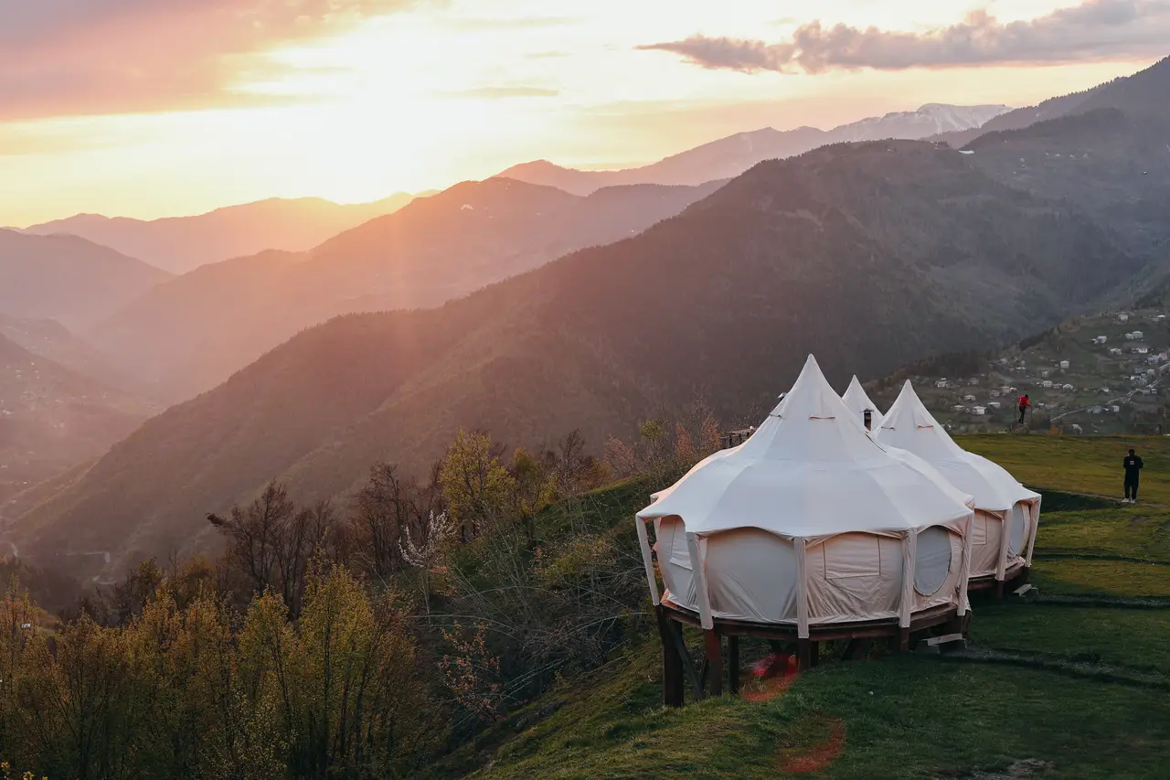 Три белые палатки на хребте Glamping Tago над долиной на закате