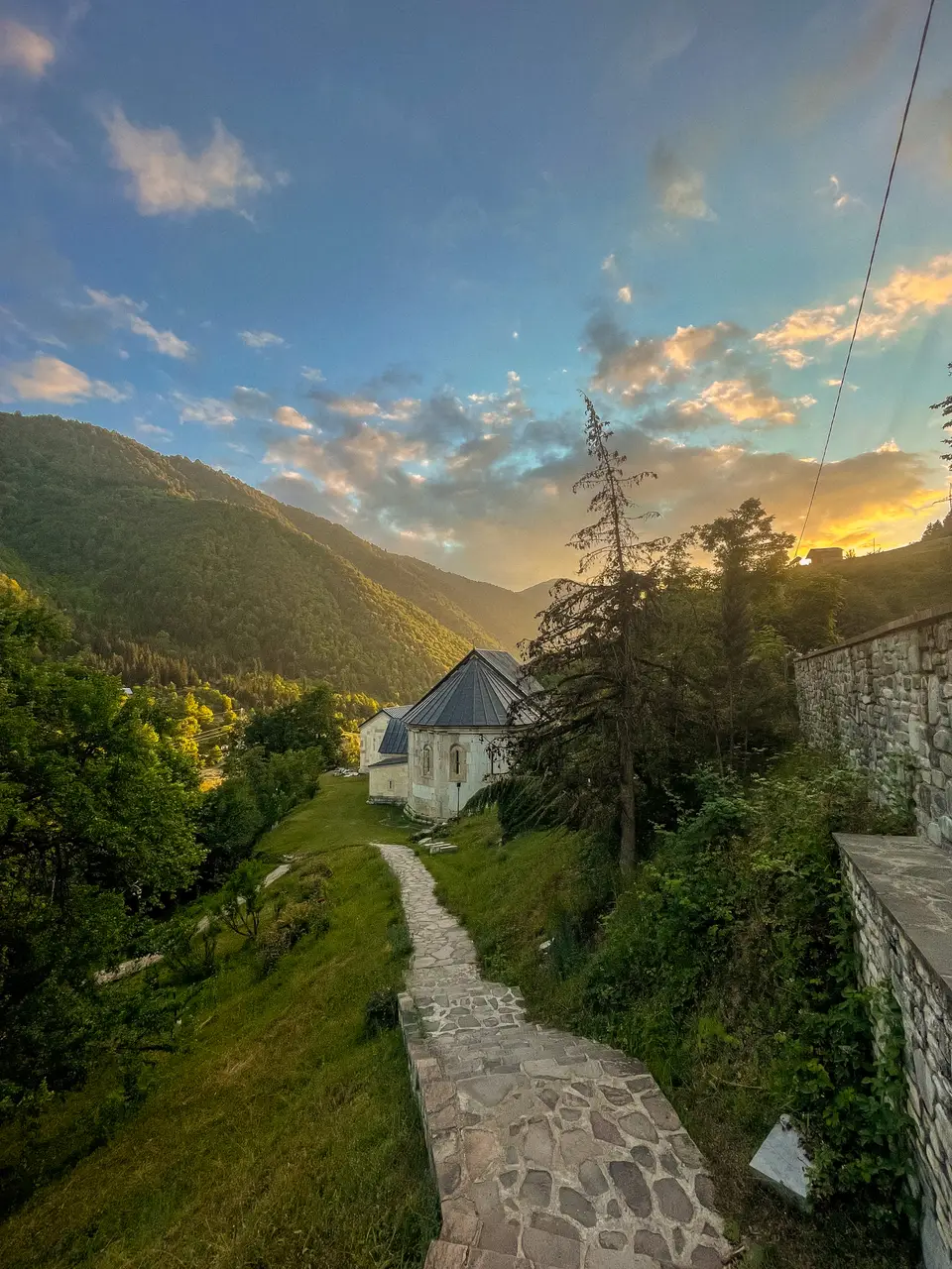 A stone path leading down to Skhalta monastery in the valley at sunset