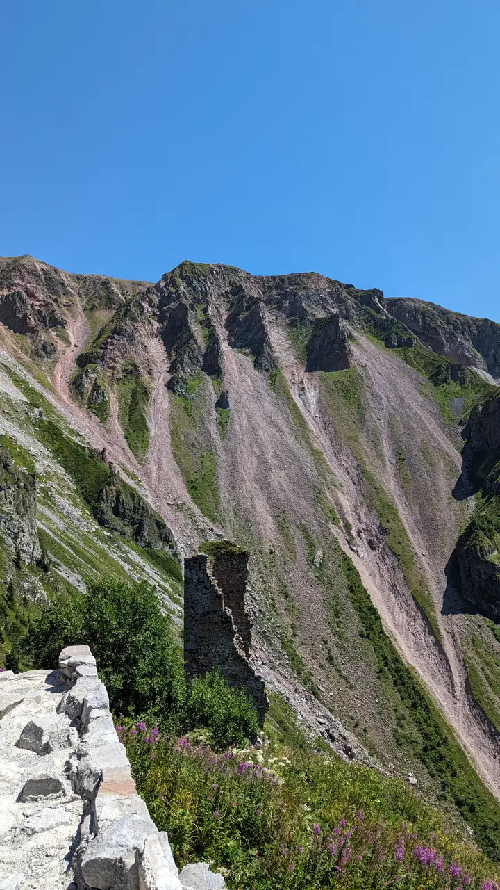 Steep scree slopes and cliffs around a small tower of Khikhani fortress