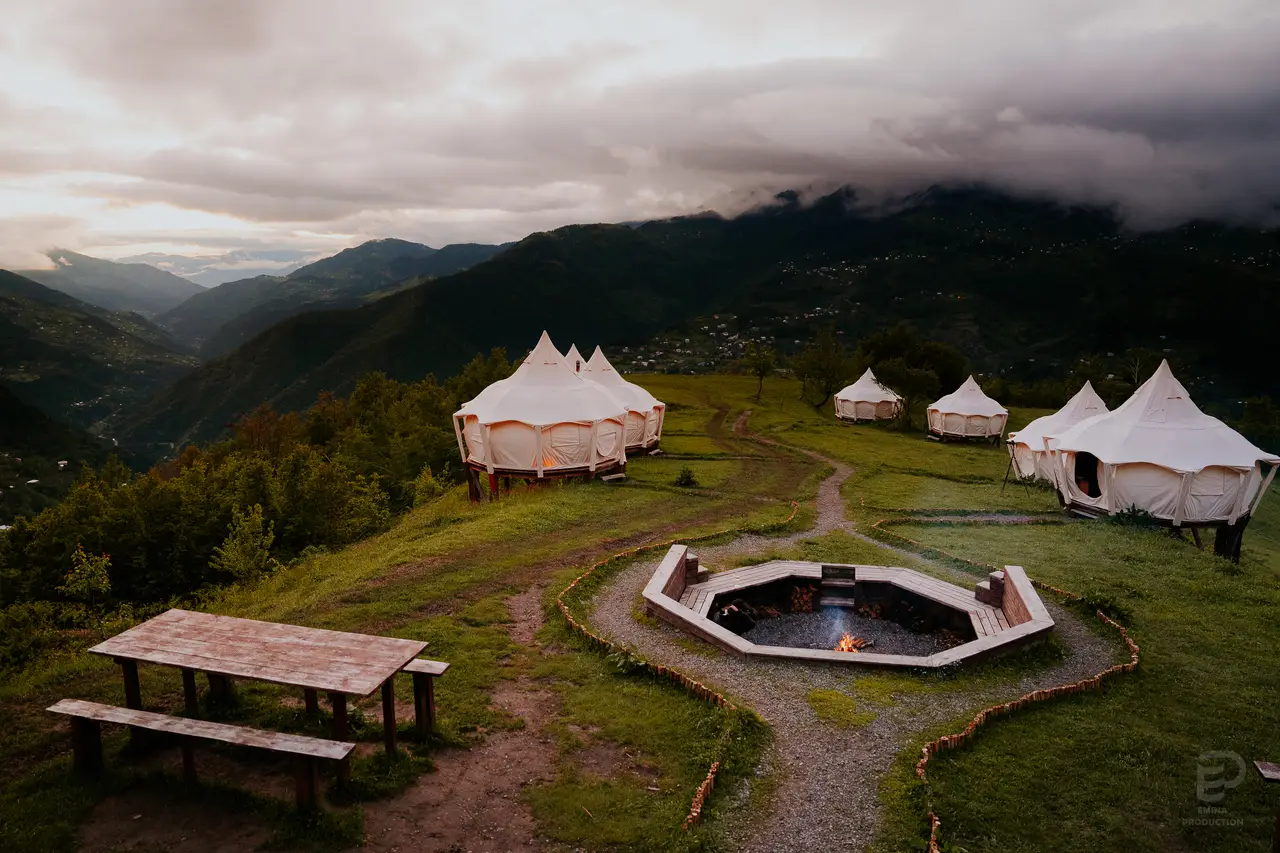 Aerial view of the white tents of Glamping Tago on a green mountain slope