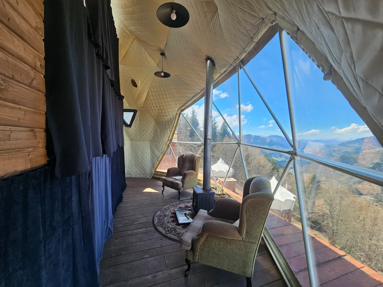 Внутри купола для йоги в Glamping Tago: кресла, дровяная печка и большие окна с видом на горы