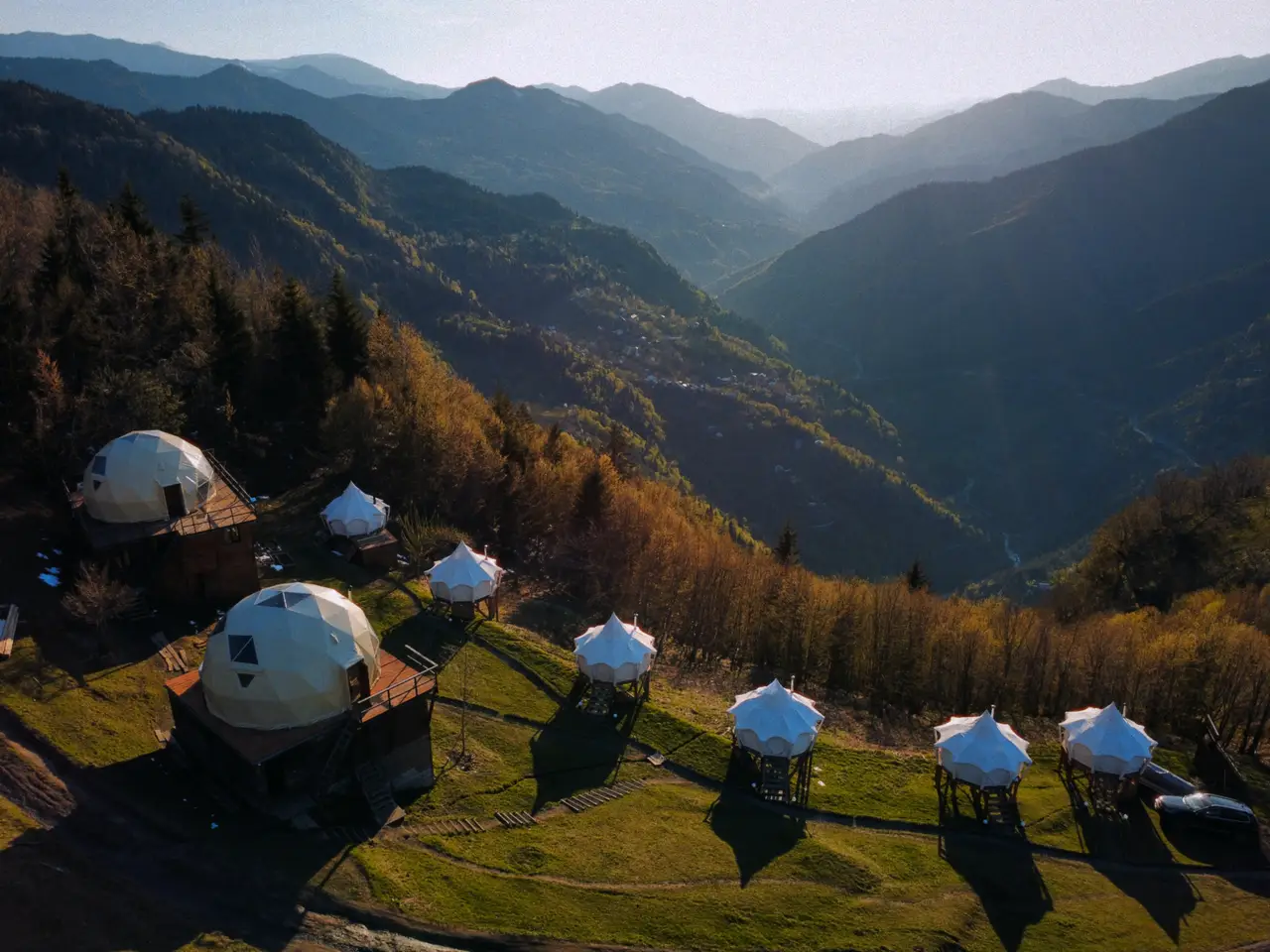 Glamping Tago-ს გუმბათები და კარვები ფერდობზე მზის ჩასვლისას, ზემოდან