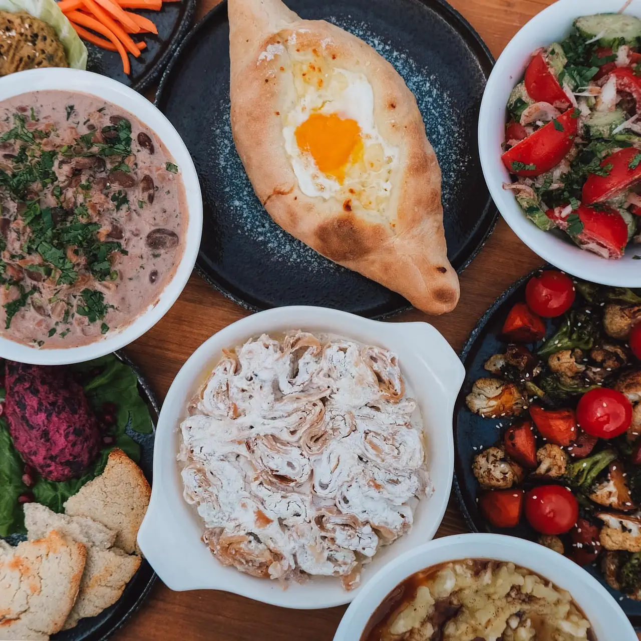 A vegetarian Georgian table with Adjarian khachapuri, lobio, pkhali, salad and roasted vegetables