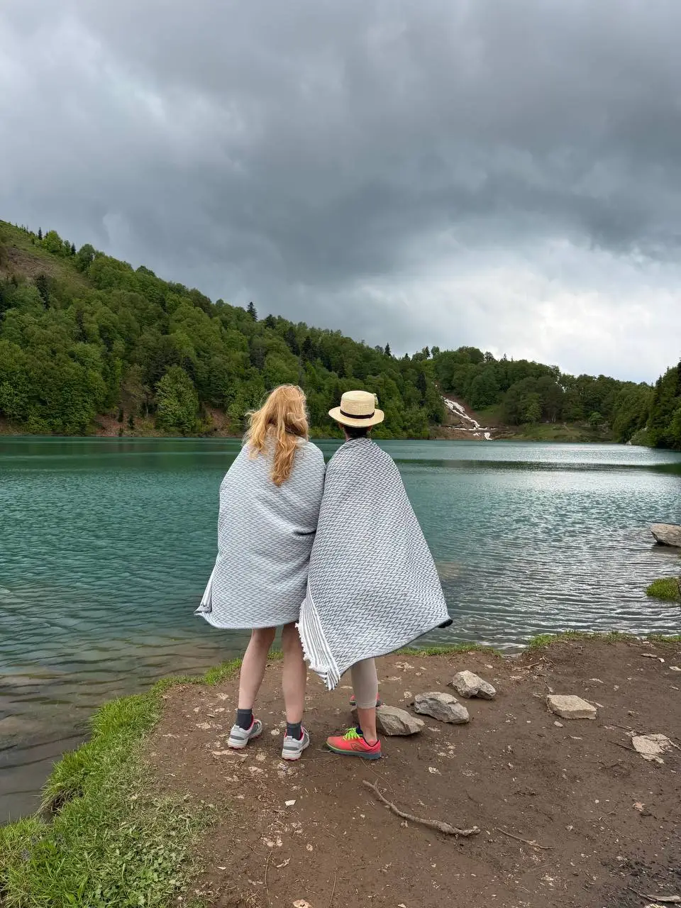 Two people wrapped in blankets looking out over Green Lake