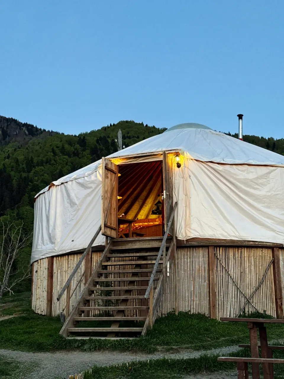The Yurtalicious yurt restaurant lit from inside at dusk, with the Adjara mountains behind
