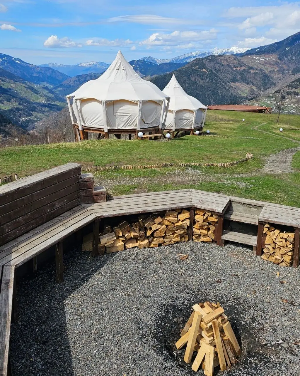 Два шатра Lotus Belle в Glamping Tago на зелёном склоне над горами Аджарии, впереди место для костра
