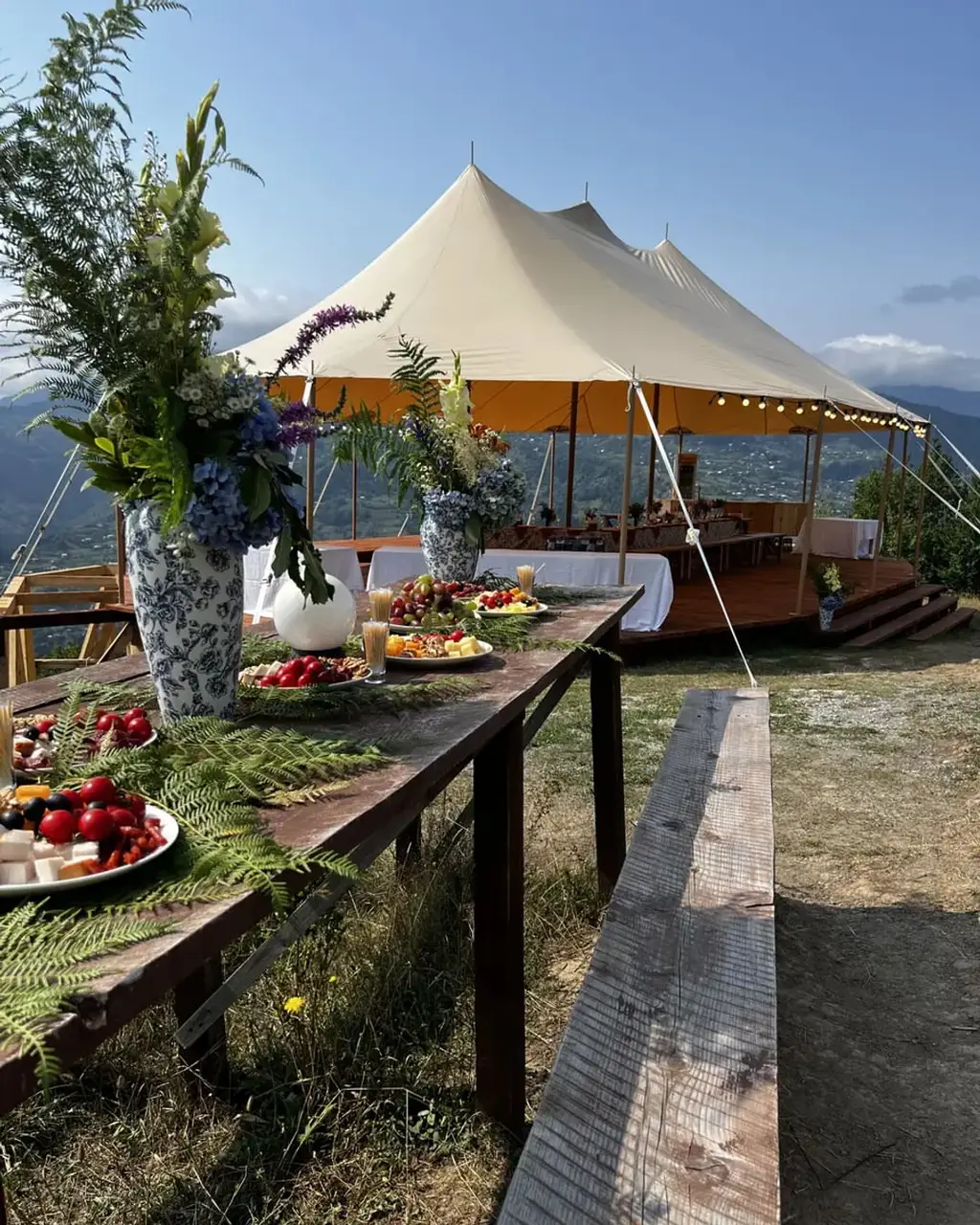 Wedding dinner tables under the event tent with the mountains behind